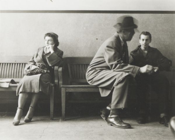 Unidentified people waiting or conferring, possibly lawyer and clients at a courthouse.