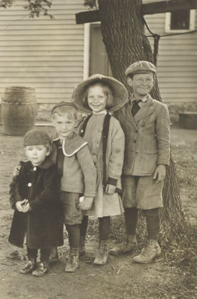 Four grinning children in the yard of a residence, identified only as the children of “Keith and Mabel”.