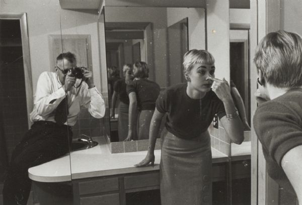 John Newhouse, staff photographer for the "Wisconsin State Journal," in a “shooting session” with model Jean Harris. Ms. Harris is, for some unexplained reason, placing a forefinger to her nose.