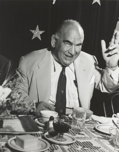 Unidentified middle-aged man at a banquet, waving.