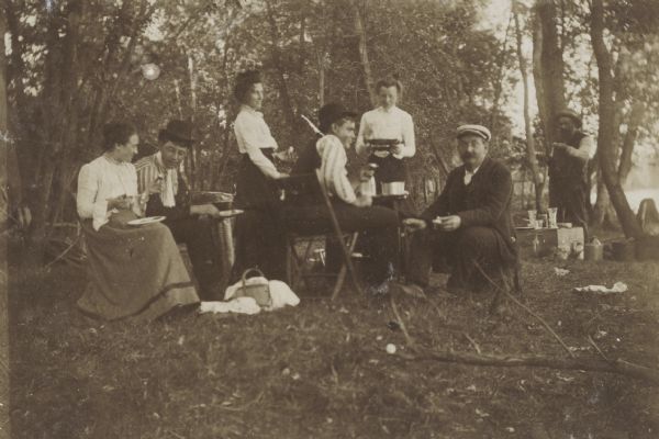Picnicking group of men and women along the shore of the Wisconsin River.