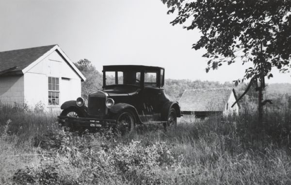 Old Ford coupe in a farm setting.