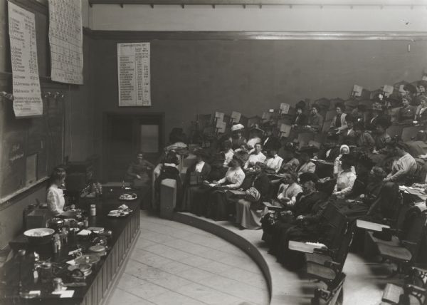 Large group of farmers' wives listening to a lecture demonstration on nutrition or cooking in a classroom at the University of Wisconsin.