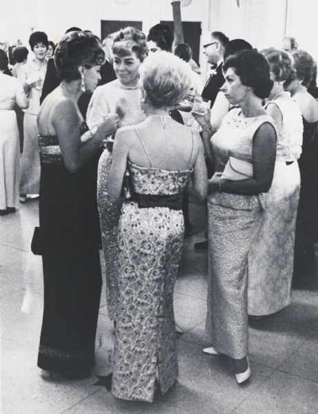 Group of four standing women conversing informally at a social occasion.