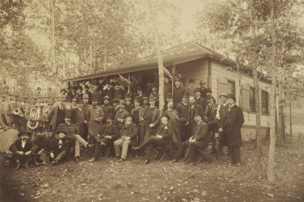 Posed group portrait outdoors of members of the Rex Magnus Club and representatives of the “Press of the United States” whom they are entertaining.