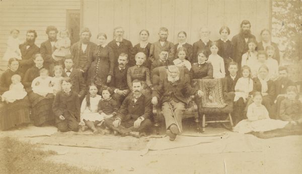 A group portrait of about 40 members of the Lloyd Jones family. The empty chair in the front row was placed in memory of the wife of Richard Lloyd Jones.<p>In the back row, from the left are: Enos holding Chester, James holding Scott, John, Nettie, Thomas B. Jones, Margaret, Thomas, Esther, William Carey Wright and his wife Anna (Frank Lloyd Wright's parents), James Philip, and Mary. In the middle two from the left are Elinor holding Agnes, Laura holding Maud, J. Richard holding Gwen, Orren, Ellen, Edward, M. Helen, Jane (with her niece Jane standing behind her), Elsie, Margaret, and Anna Nell. In the front row from the left are Thomas, Mary, Jenkin, Charles, Richard, Frank Lloyd Wright holding his sister Maginel, Susan with Mary Lloyd at her feet, and Jenkin with Richard at his feet.
