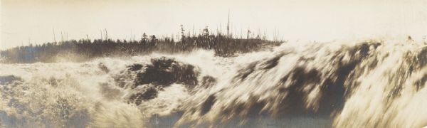 Semi-panoramic view of rapids, water pouring near the dam of the Great Northern Paper Company.
