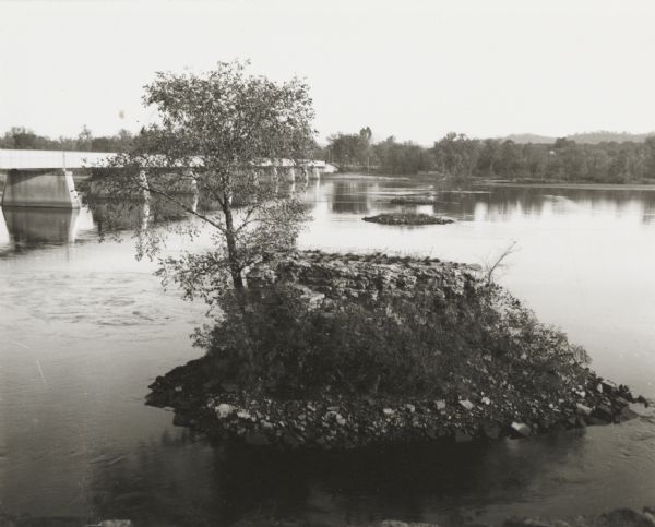 Cement and steel bridge over the Wisconsin River. Alongside are the ruined stone foundations of the former bridge.
