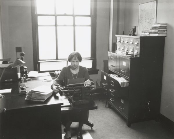 Young woman sitting at a typewriter, presumably a staff employee, in the office of the Indiana Liberty Mutual Insurance Company.