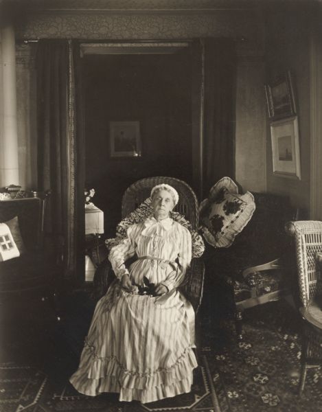 Portrait of Mrs. Harry Adams seated in a residential interior. She is holding a flower in her lap.