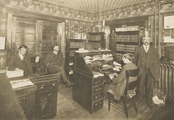 Unidentified office interior, with members of the male staff. In the foreground on the left is an open safe. The inside of the door reads: "Hall's Patent."