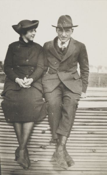Young couple seated outdoors on what appears to be a pile of lumber.