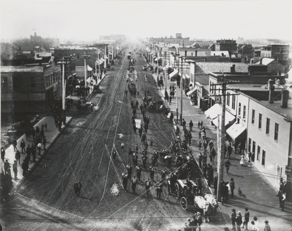 Elevated view of parade, looking down a broad street. It has been suggested but not verified that this view is in Superior, Wis.
