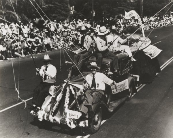 Slightly elevated view of celebrants at an American Legion convention parade riding on a float made to represent Wisconsin fishing.