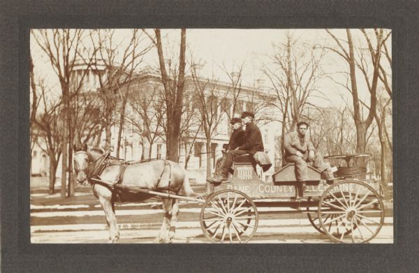 Dane County Telephone Co. horse-drawn service and installation wagon. The Wisconsin State Capitol is in the background. “Dad” Schroeder and Oscar Quale are on the front seat of the wagon; Mr. Smith is riding on the tool box.