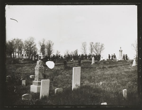 Large group, posed at a distance, in a cemetery, probably in Hixton or Schlecterville.
