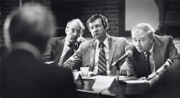 Congressman Les Aspin (right) and David R. Obey (center) at a public hearing. Although undated, the photograph was taken by Gary Porter of the "Janesville Gazette" and so it was probably taken there.