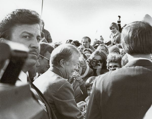 President Jimmy Carter shaking hands in Wausau, while the Secret Service (left) keeps watch.