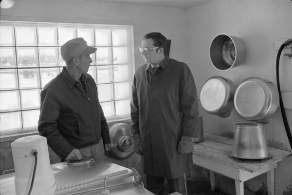 As part of a campaign photo shoot, Laurence Day gives candidate David R. Obey a tour of his dairying operation in Marathon County. Day was both a dairy farmer and a member of the Wisconsin Assembly.