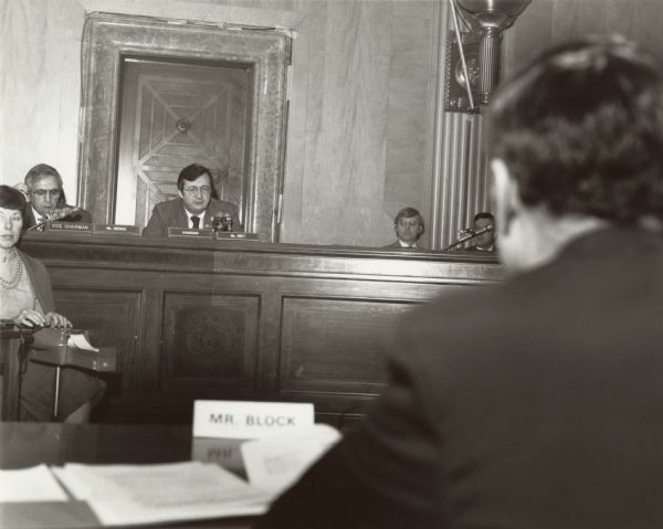 David R. Obey of Wisconsin, chair of the Joint Economic Committee. Opposite him, (in the foreground) is Secretary of Agriculture John R. Block, testifying about the problems facing farmers and the rural economy. A recording secretary sits on the far left.