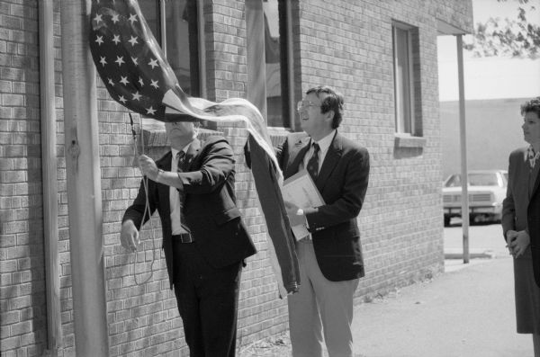 Federal officials frequently delivered flags flown over the U.S. Capitol to organizations in their district. Here, Congressman David R. Obey of Wisconsin assists with raising a new flag. Although the location is unidentified, it is thought to be the Athens post office.