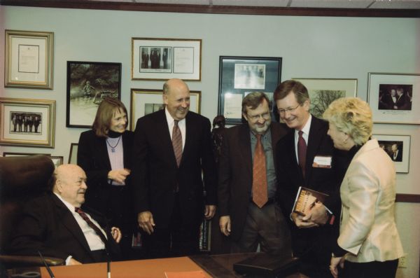 Former Wisconsin congressman and defense secretary Melvin Laird seated at the replica of his former offices built by the Marshfield Clinic as part of the Laird Center for Medical Research. Among the memorabilia of Laird's career housed at the Center is the desk of former Speaker Joseph E. Cannon that Laird used from 1958 until he retired from the "Reader's Digest." With Laird are Governor and Mrs. James Doyle and Congressman David R. Obey. The two people standing to Obey's right are Mark Bradley, a member of the UW Board of Regents, and State Supreme Court Justice, Ann Walsh Bradley.