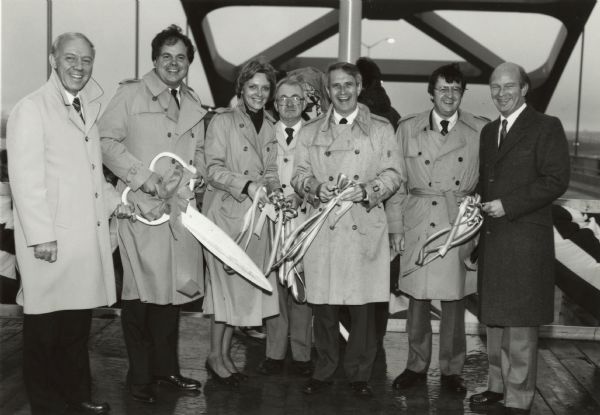 Ribbon-cutting ceremony for the Bong Bridge. Identified officials present include Congressman James Oberstar (Minnesota), Senator Robert Kasten (2nd from left with large scissors), Wisconsin Governor Tony Earl (3rd from right), and Wisconsin Congressman David R. Obey (second from the right).