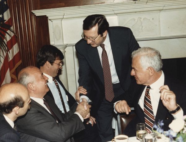 Congressman David R. Obey (standing) of Wisconsin shakes hands with former Soviet President Mikhal Gorbachev at a diplomatic luncheon in Washington. Also with them are Congressman Tom Downey (looking away from the camera) and Speaker of the House Thomas Foley. An interpreter is on the far left.