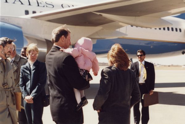 Vice President Al Gore holds an unidentified child for a photograph at the Wausau Airport. Gore was in town to speak to the Better Way Club.  Wisconsin Congressman David R. Obey is at the left.