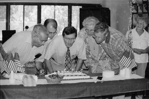At a celebration for the 30th anniversary of Medicare, Wisconsin Congressman David R. Obey and guests blow out the candles on a cake.