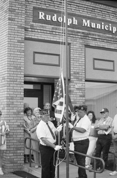 Local members of the VFW raise a new flag in front of the Rudolph Municipal Building. The flag, which had flown over the U.S. Capitol, was presented by Congressman David R. Obey.