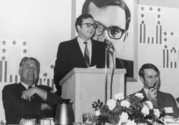Wisconsin Congressman David R. Obey speaking at a testimonial dinner marking the first anniversary of his election to Congress. To his right is Mayor Ralph Voight, and to his left is Anthony Earl who was elected to fill Obey's Assembly seat and eventually elected governor of Wisconsin.