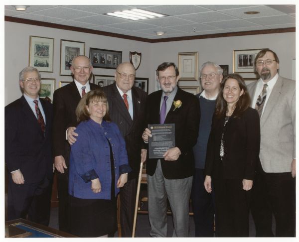 Congressman David Obey receives an award from the Marshfield Clinic Heritage Foundation. He is wearing a yellow rose boutonniere on his lapel. To Obey's right is former Wisconsin Congressman and Secretary of Defense Melvin Laird. They are standing in front of the desk in the replica of Laird's former office built by the Marshfield Clinic as part of the Laird Center for Medical Research.