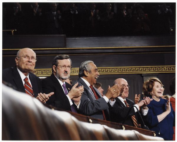 Congressman David Obey stands in a row and applauds at the State of the Union address. To Obey's left are Congressman Charles B. Rangel of New York and Congressman Henry Waxman of California.