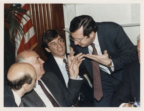 Congressman David R. Obey (standing) leans over to speak with former Soviet President Mikhal Gorbachev at a diplomatic luncheon in Washington. Also with them are Congressman Tom Downey and Speaker of the House Thomas Foley (barely seen on the right). An interpreter is on the left.
