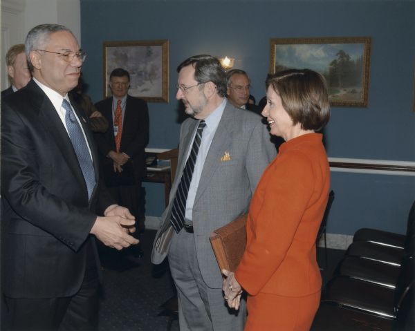 Secretary of State Colin Powell, Congressman David Obey and and Congresswoman Nancy Pelosi stand together at a gathering.