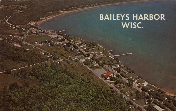 Aerial view of commercial buildings and dwellings along the shore of Lake Michigan. Caption reads: "Baileys Harbor, Wisc."