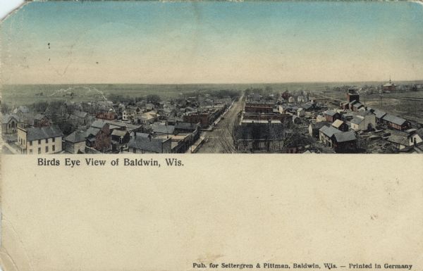 Colorized panoramic elevated view with the main commercial district in the center. The high school is on the far right. Caption reads: "Birds [sic] Eye View of Baldwin, Wis."