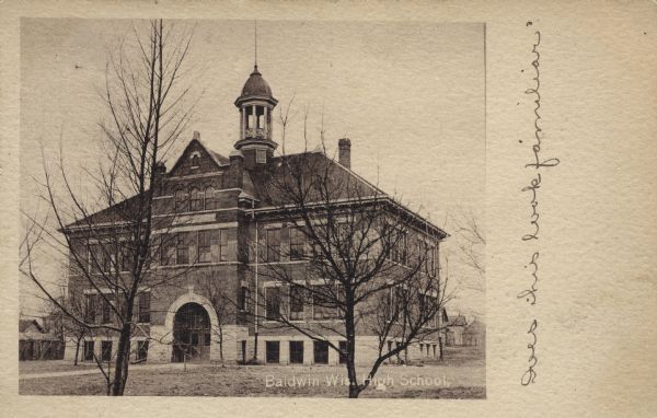 Photographic postcard view of the exterior of the high school. There is a cupola over the belfry and an arched doorway. Caption reads: "Baldwin, Wis. High School."Handwritten on the right: "Does this look familiar?"