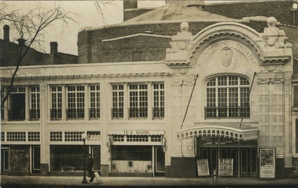 Photographic postcard view of the exterior of the theater. There are posters in front of the entrance. A current attraction is George Fawcett in "The Frame-Up" (1915). A policeman is standing next to the Tea Room on the left.
