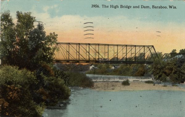 Colorized postcard view of a bridge over a dam on a river. Trees are along both banks. Caption reads: "The High Bridge and Dam, Baraboo, Wis."