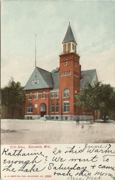 Colorized postcard of an exterior view of City Hall, a brick building with an arched entrance, a flag pole on the left, and a belfry on the right. Caption reads: "City Hall, Baraboo, Wis."