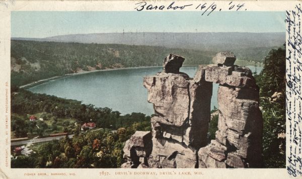 Colorized postcard view of the Devil's Doorway rock formation overlooking Devil's Lake. Caption reads: "Devil's Doorway, Devil's Lake, Wis."