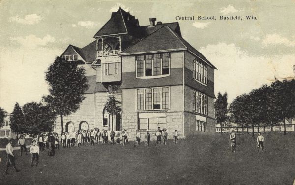 View of the exterior of the school, with students standing on the front lawn. Caption reads: "Central School, Bayfield, Wis."
