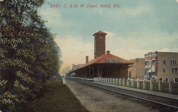 Colorized postcard view of a depot with a clock tower. Commercial buildings are on the right. Caption reads: "C. & N. W. Depot, Beloit, Wis."