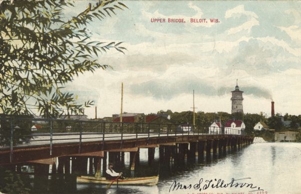 Colorized postcard view from riverbank of the Upper Bridge crossing the Rock River into Beloit. A man is in a rowboat in the foreground. In the background rising above the trees is a tower and a smokestack. Caption reads: "Upper Bridge, Beloit, Wis."