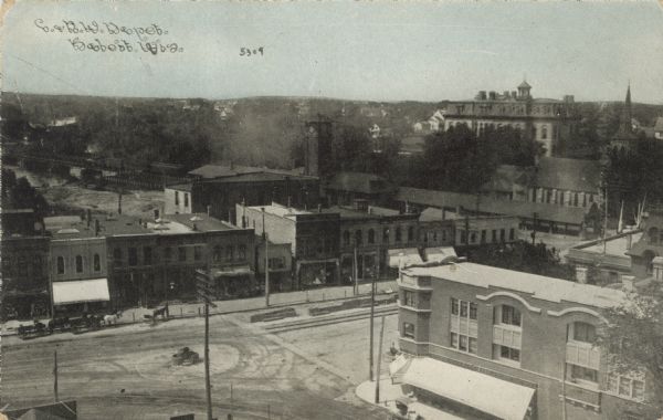 Elevated view of a train depot surrounded by a central business district. Horses and wagons are in the street in the foreground. Caption reads: "C. & N.W. Depot, Beloit, Wis."