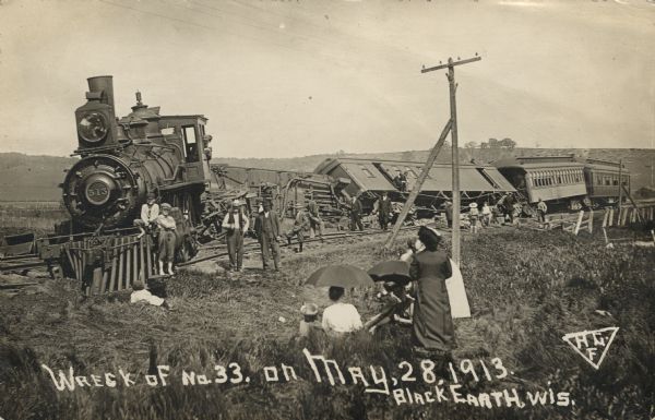 Photographic postcard view of the aftermath of a train wreck. Survivors and onlookers are gathered on and around the railroad tracks. Caption reads: "Wreck of No. 33 on May 28, 1913. Black Earth, Wis."