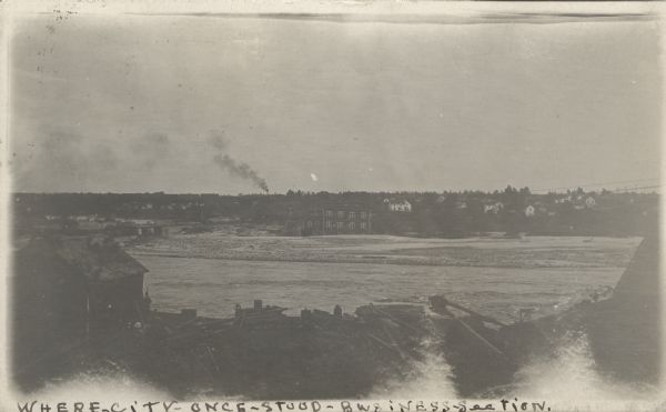 Photographic postcard view of the devastation after a flood in central Black River Falls. Caption reads: "Where City Once Stood - Business Section."