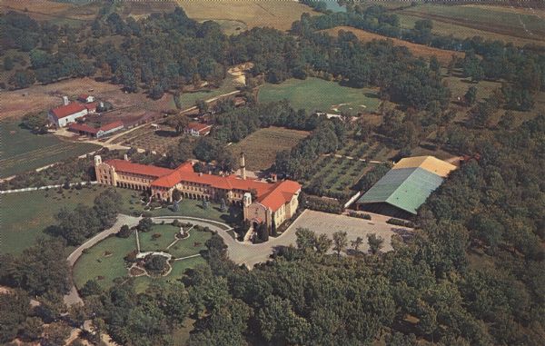 Aerial view of a monastery and college with other buildings and landscaping.